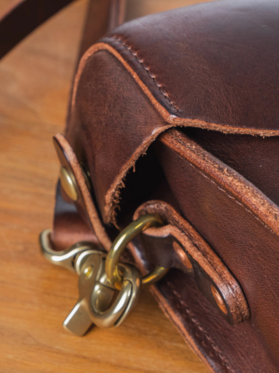 Close-up of solid brass buckle and hand-burnished edges on Italian full-grain bag