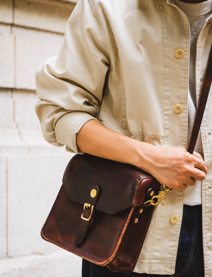 Dark brown Italian leather crossbody satchel styled with beige jacket and jeans