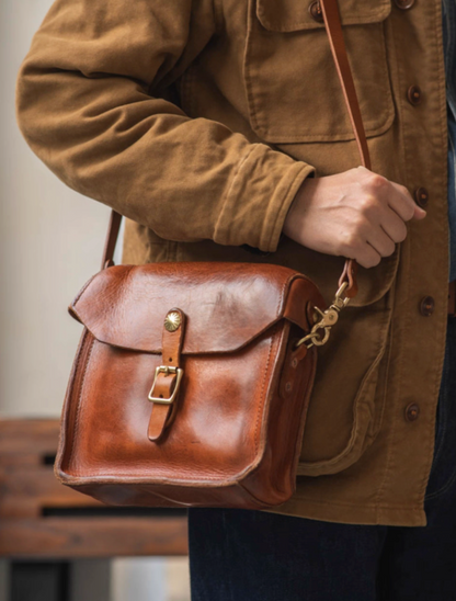 Side view of light brown handcrafted leather satchel with brass buckle and strap