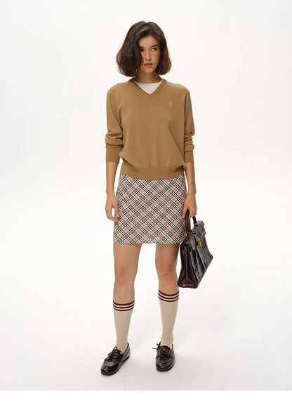 Full-body view of Camel Brown wool V-neck sweater paired with plaid skirt and loafers