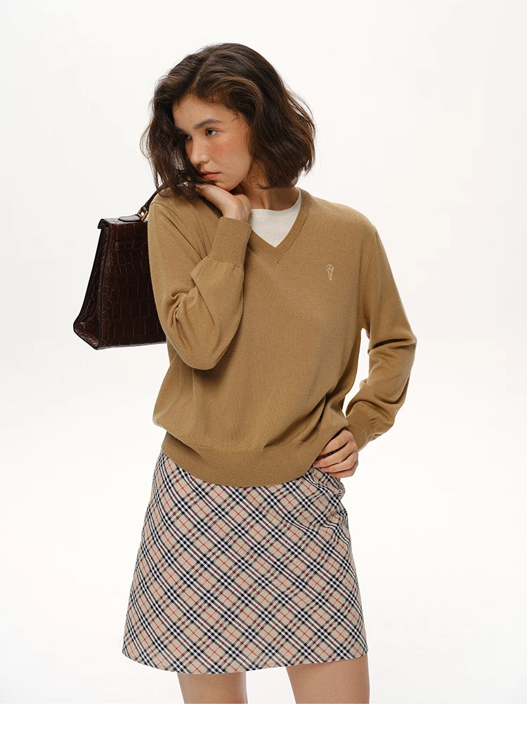 Camel Brown layered-look wool V-neck sweater styled with plaid skirt and handbag