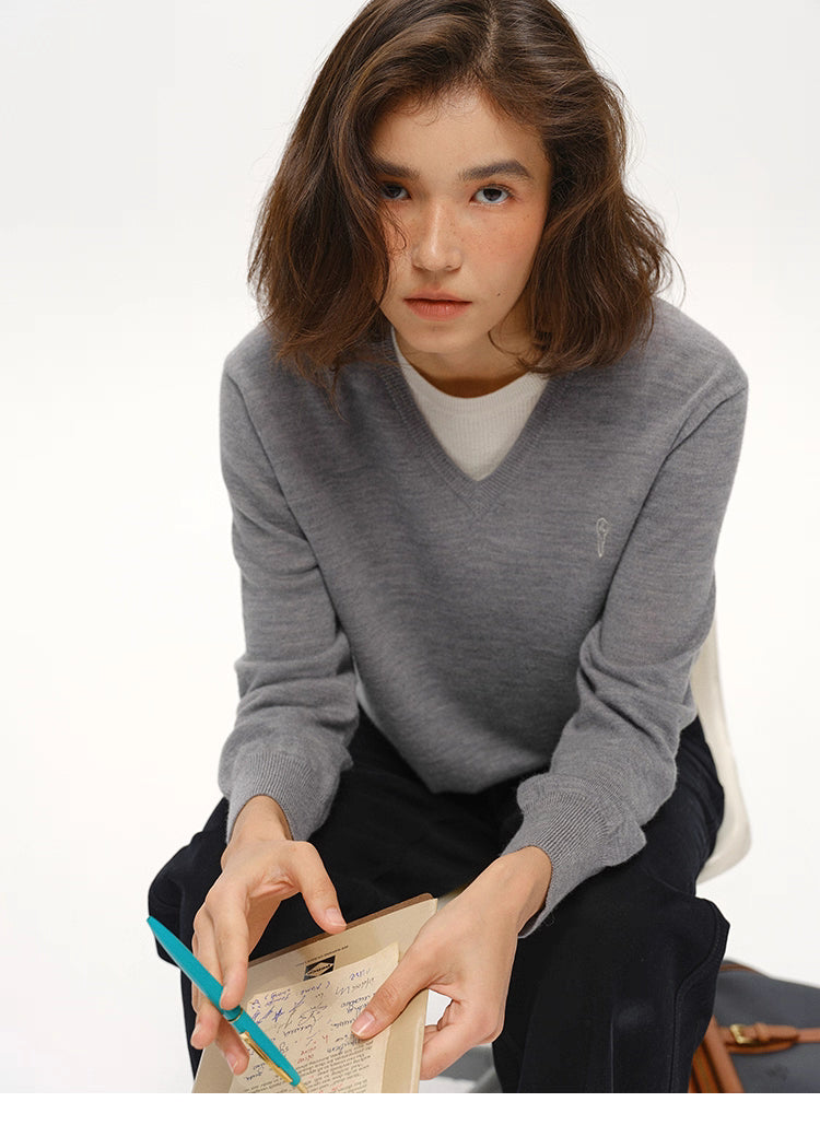 Heather Gray wool V-neck sweater in seated pose with notebook, minimalist styling