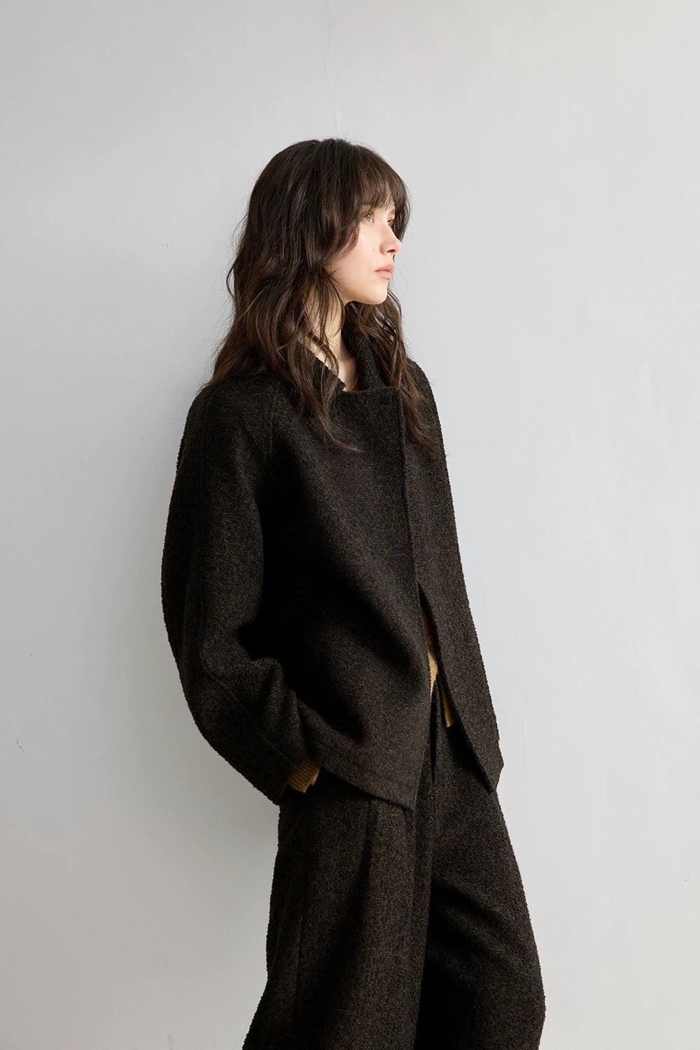 Side profile of a Dark Brown boxy bouclé jacket with wide raglan sleeves