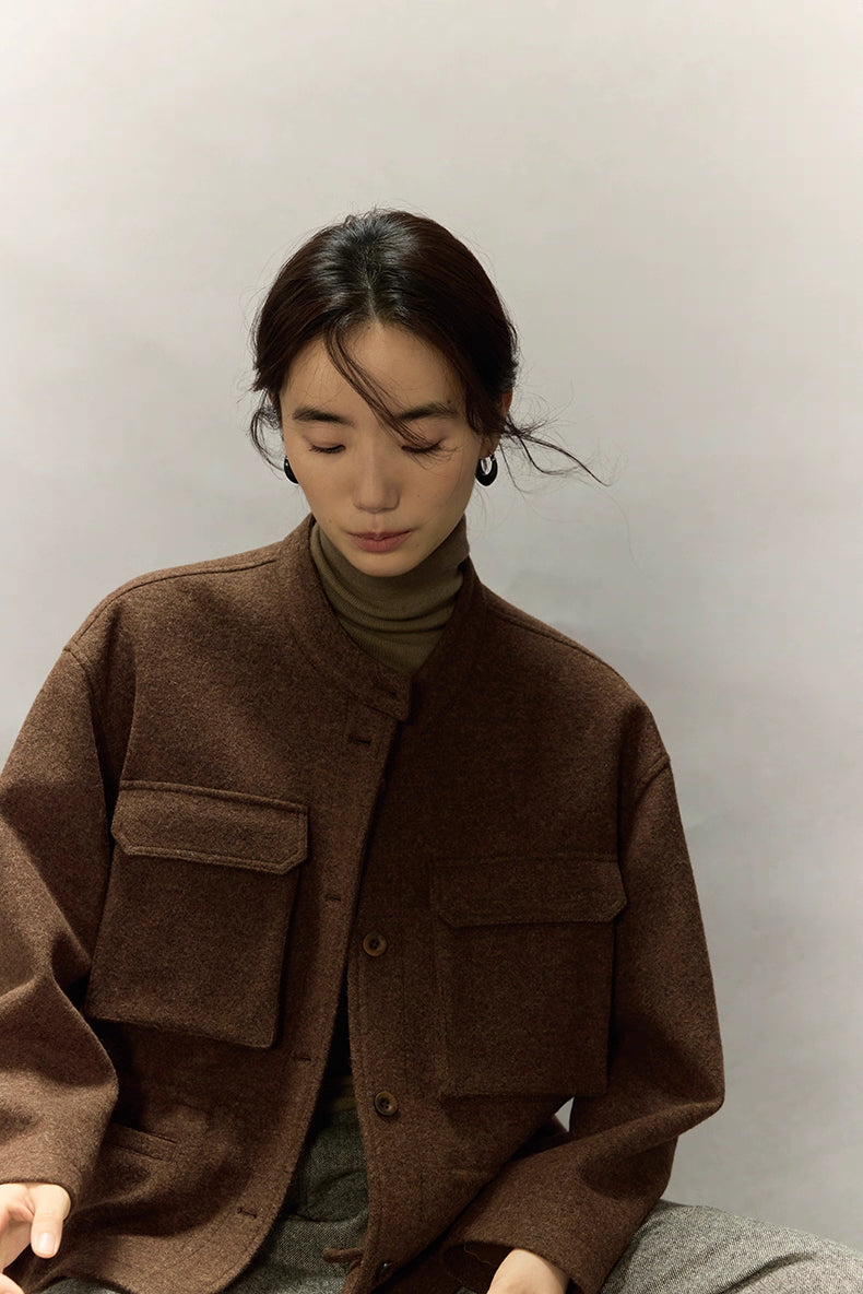 Woman sitting and looking down while wearing dark coffee wool field jacket with large utility pockets