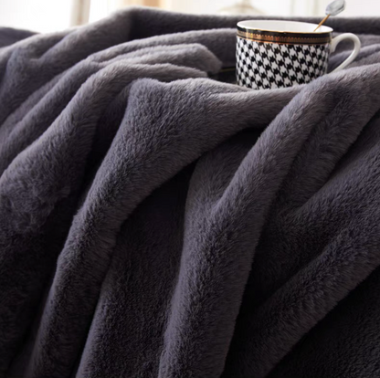 Close-up of dark gray faux fur throw blanket showing dense soft luxury fabric texture