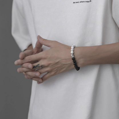 Black and white cracked lava stone bracelet worn on wrist showing dual-tone bead design symbolizing day and night