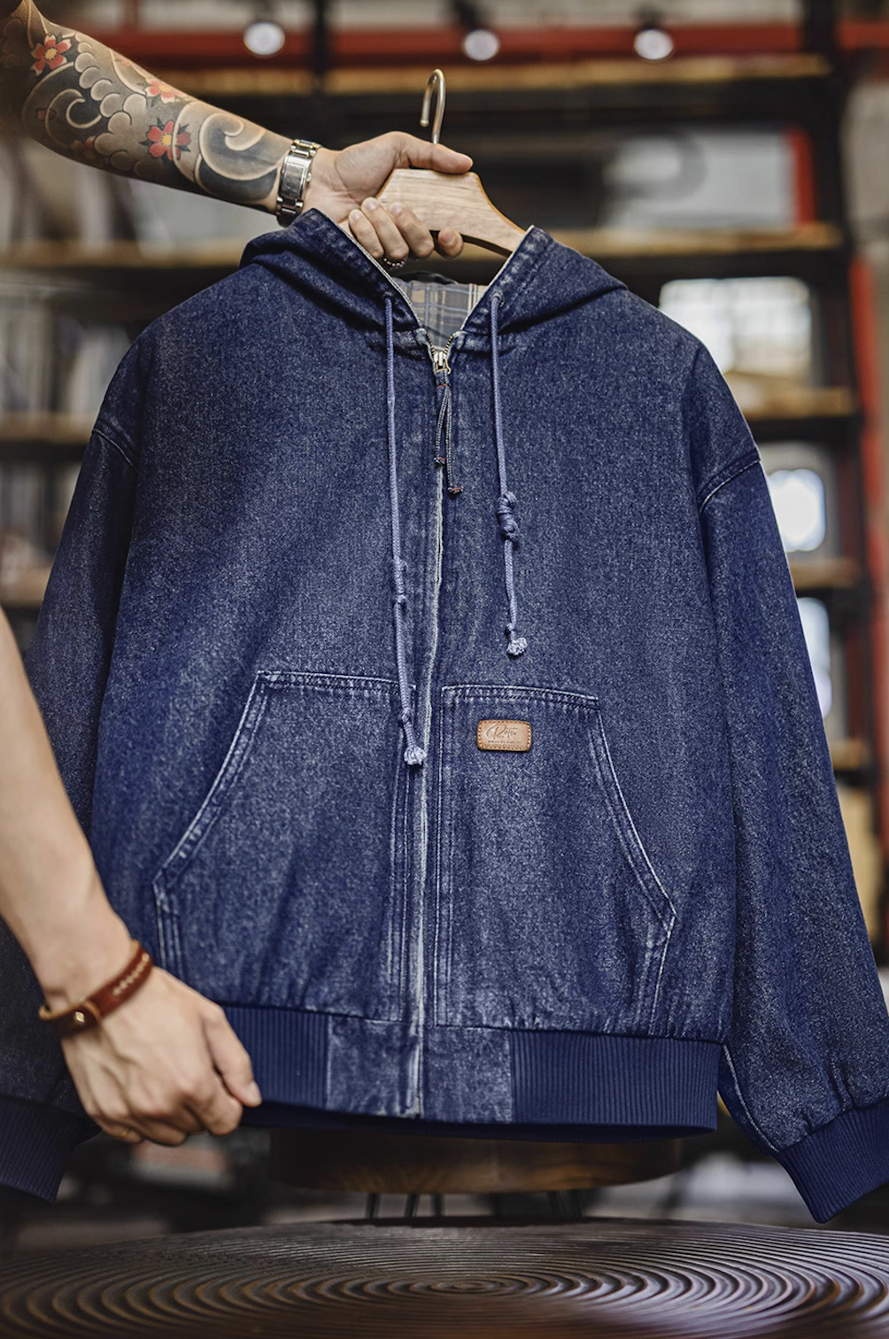 Hanging front view of denim zip hoodie showing drawcord hood and center zipper.