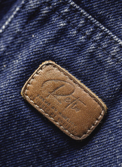 Macro shot of stitched leather logo patch near the pocket.