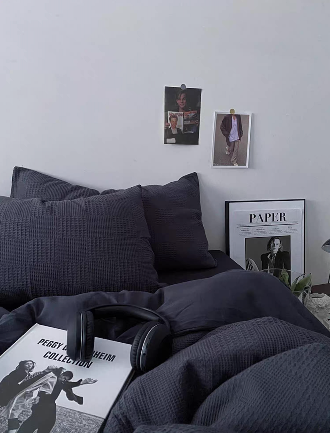 Charcoal gray diamond-waffle jacquard duvet cover set with pillows in a modern bedroom; magazine and headphones on bed.