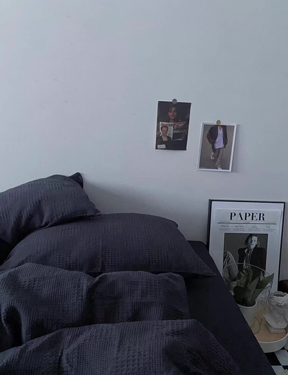 Charcoal gray textured jacquard bedding set neatly made in a minimalist room with framed poster and soft natural light.