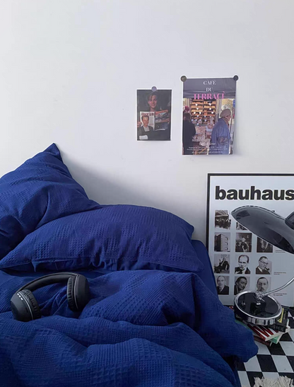 Royal blue textured jacquard bedding close-up with pillows; Bauhaus print and lamp add a clean, contemporary vibe.