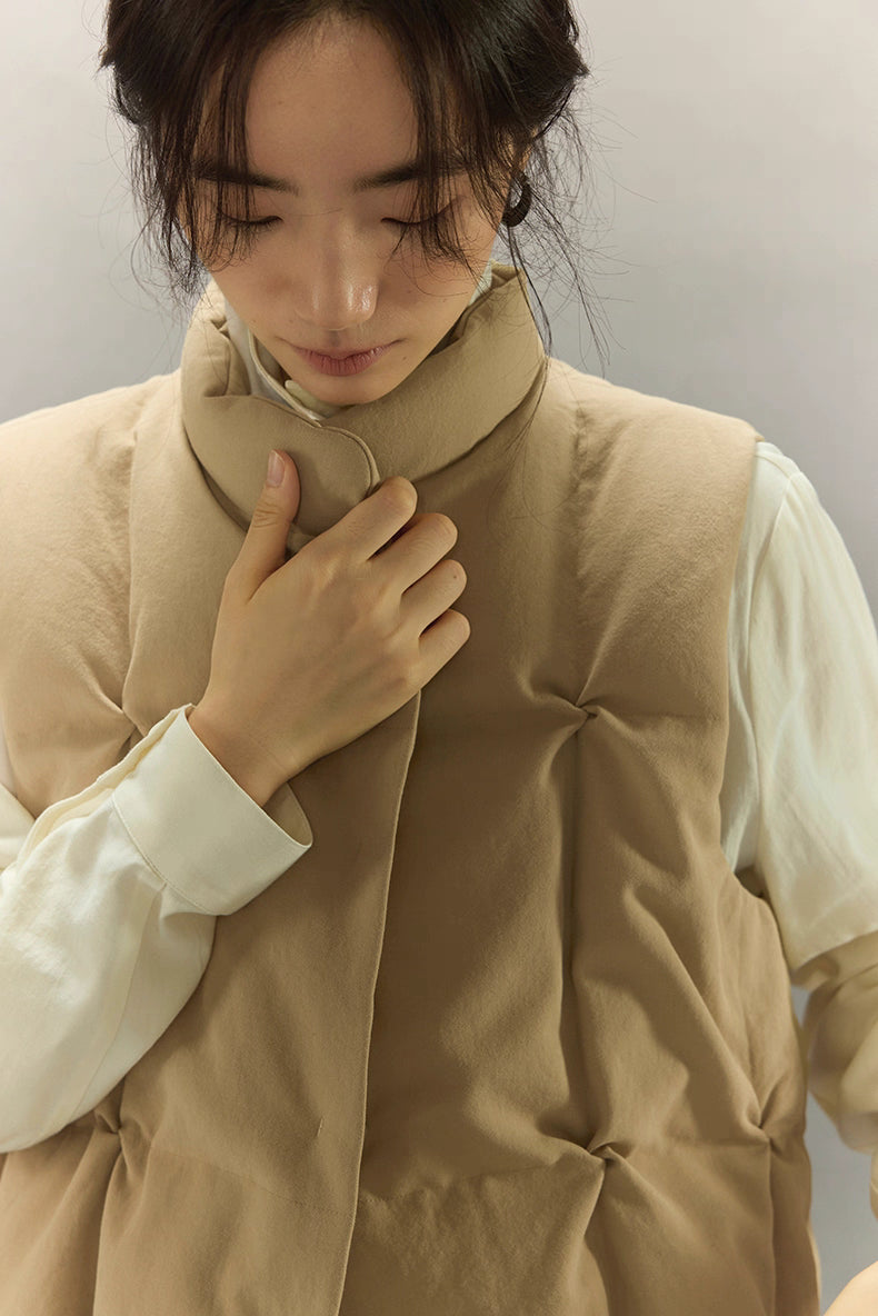 close-up of soft stand collar on beige sculpted down vest