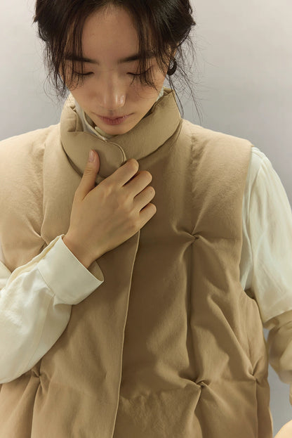 close-up of soft stand collar on beige sculpted down vest