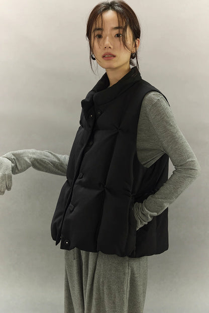 woman extending arm while wearing black sculpted quilted down vest