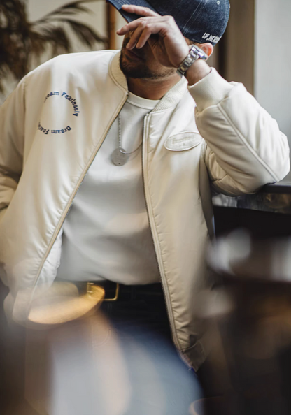 Lifestyle shot of man wearing bomber jacket leaning at bar in relaxed pose