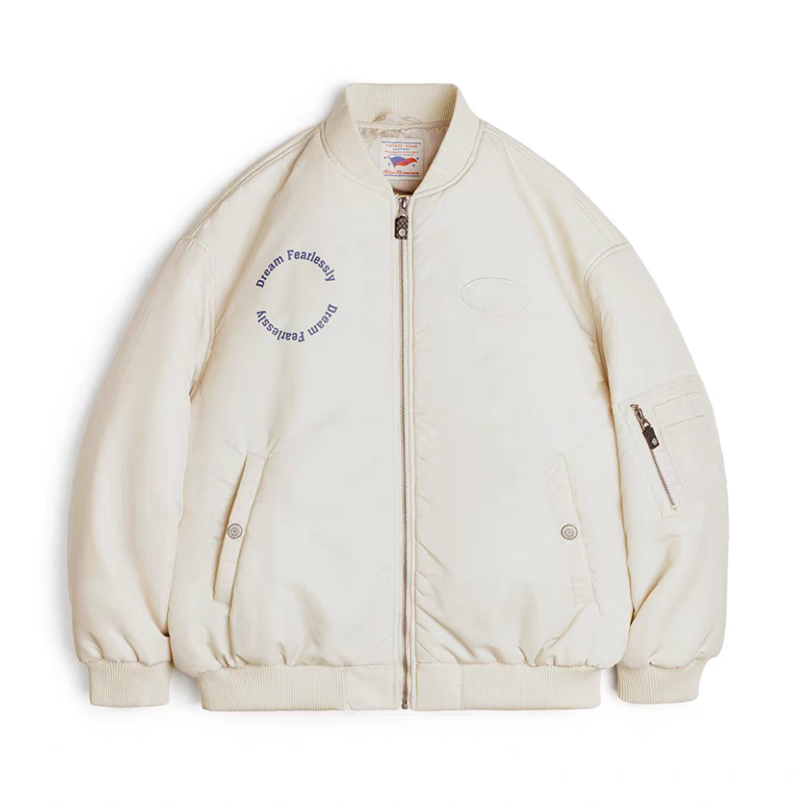 Front flat lay of cream MA-1 bomber jacket with “Dream Fearlessly” embroidery