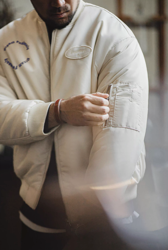 Close-up of model adjusting utility sleeve pocket zipper on bomber jacket