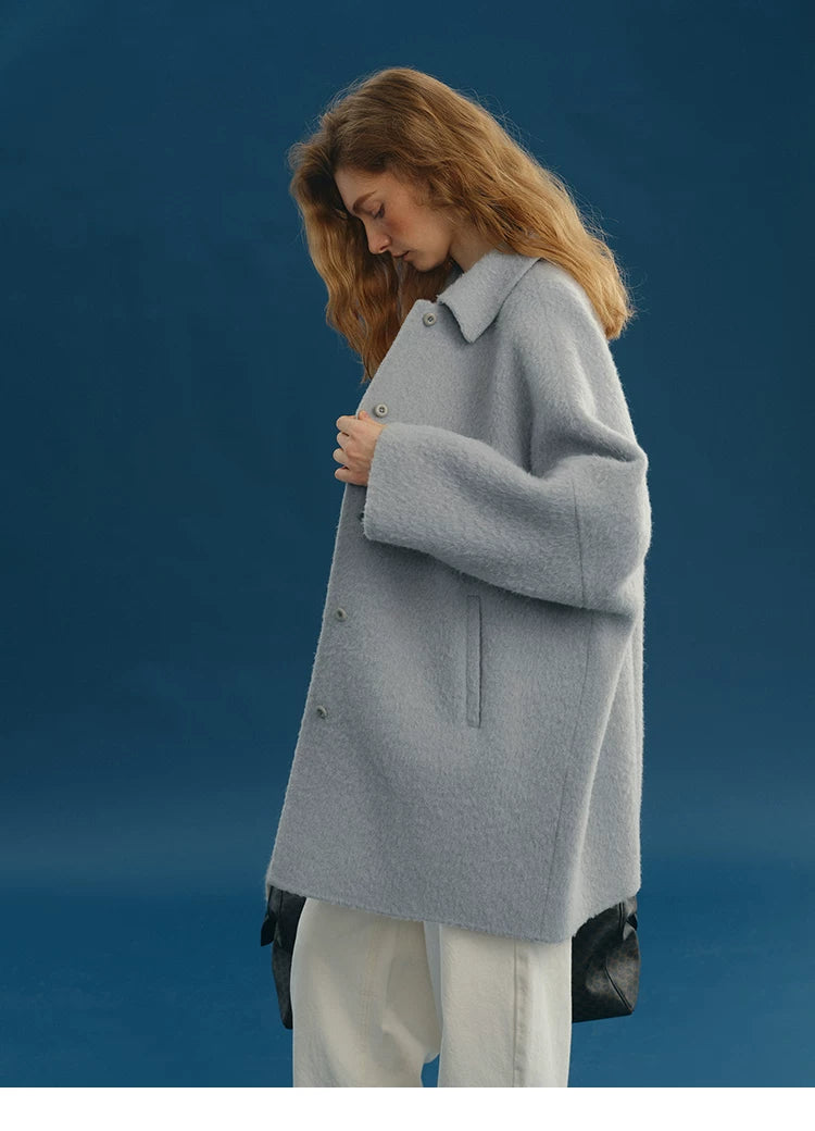 Side profile of a Dusty Blue oversized wool coat with slanted welt pocket and single-breasted buttons