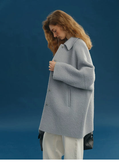 Side profile of a Dusty Blue oversized wool coat with slanted welt pocket and single-breasted buttons