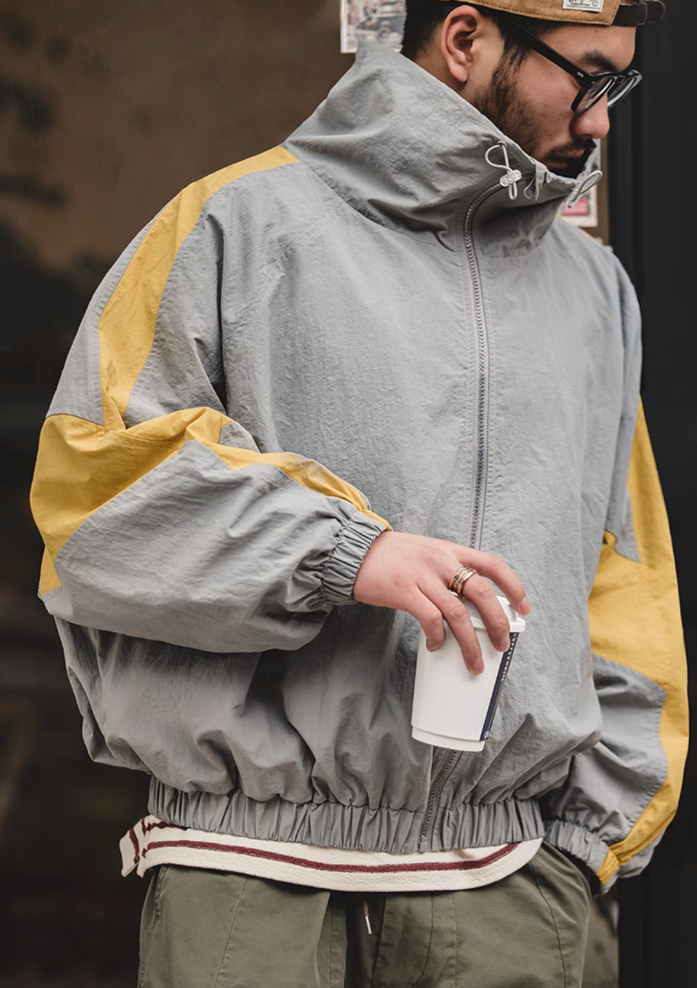 Angled front view of Scottish Grey Dynamic Layering Jacket worn by model showing color block sleeve and elastic hem