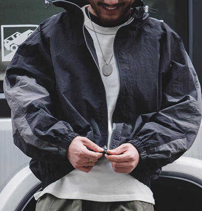 Man wearing Sumatra Black Dynamic Layering Jacket adjusting zipper highlighting dual zip design and lightweight texture