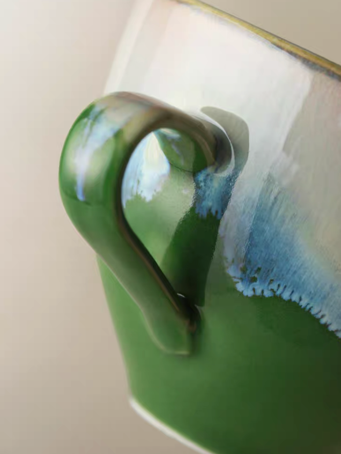 Kiln-Change Green ceramic coffee cup close-up of handle with glossy glaze blending green and blue tones