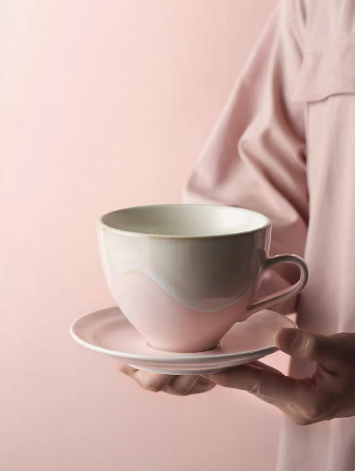 Kiln-Change Pink ceramic coffee cup and saucer held in hand showcasing elegant design and soft matte finish