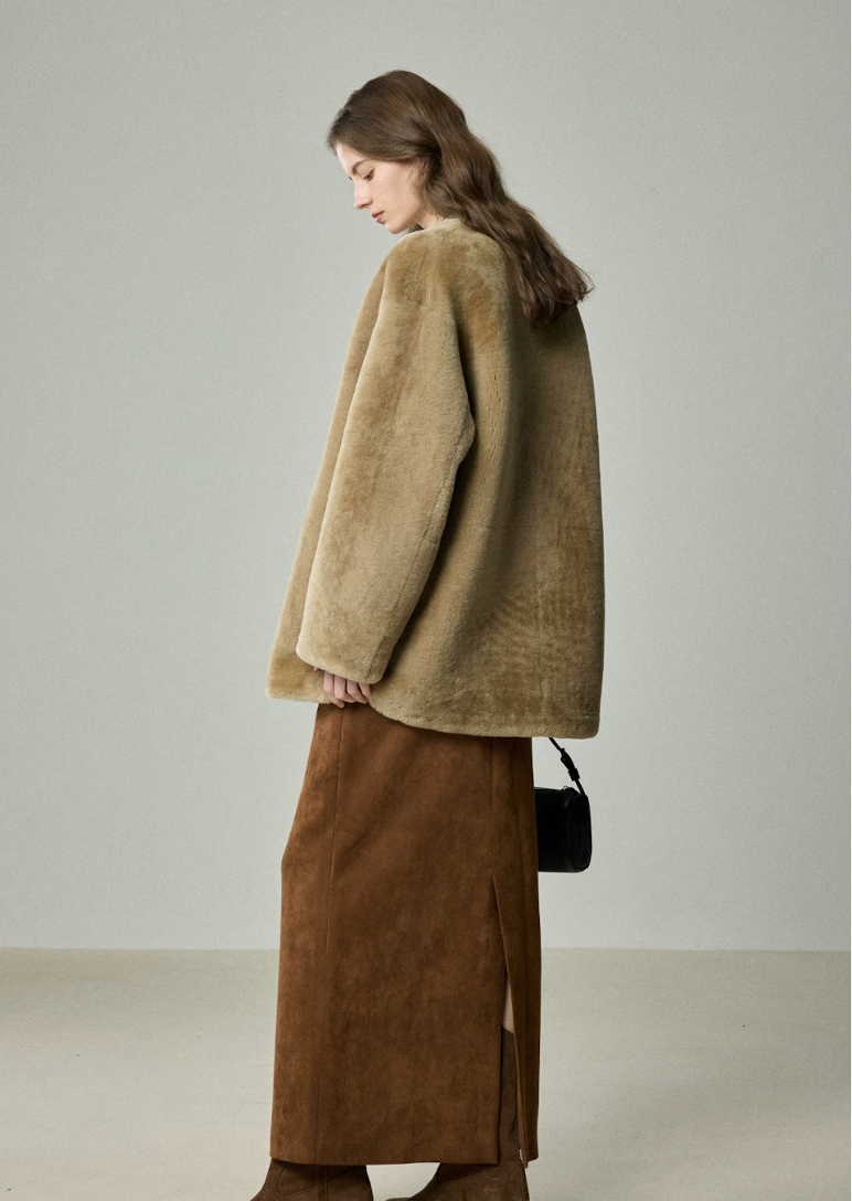 Back side view of relaxed camel shearling jacket over a long suede skirt