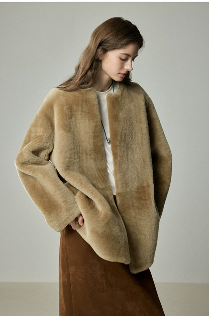 Camel edge-to-edge shearling jacket worn open with hand in side pocket