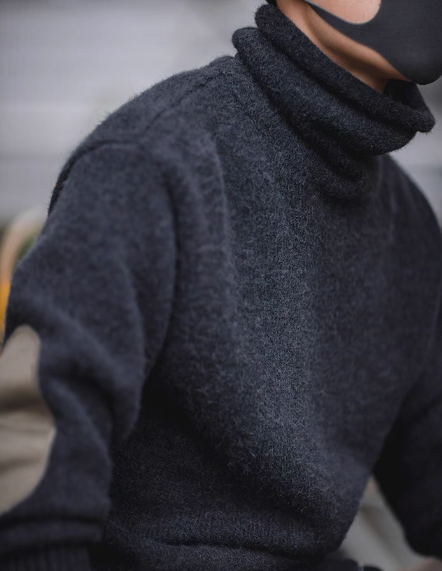 Close up of Elbow Patch Turtleneck Sweater in charcoal black highlighting soft knit texture and structured turtleneck collar