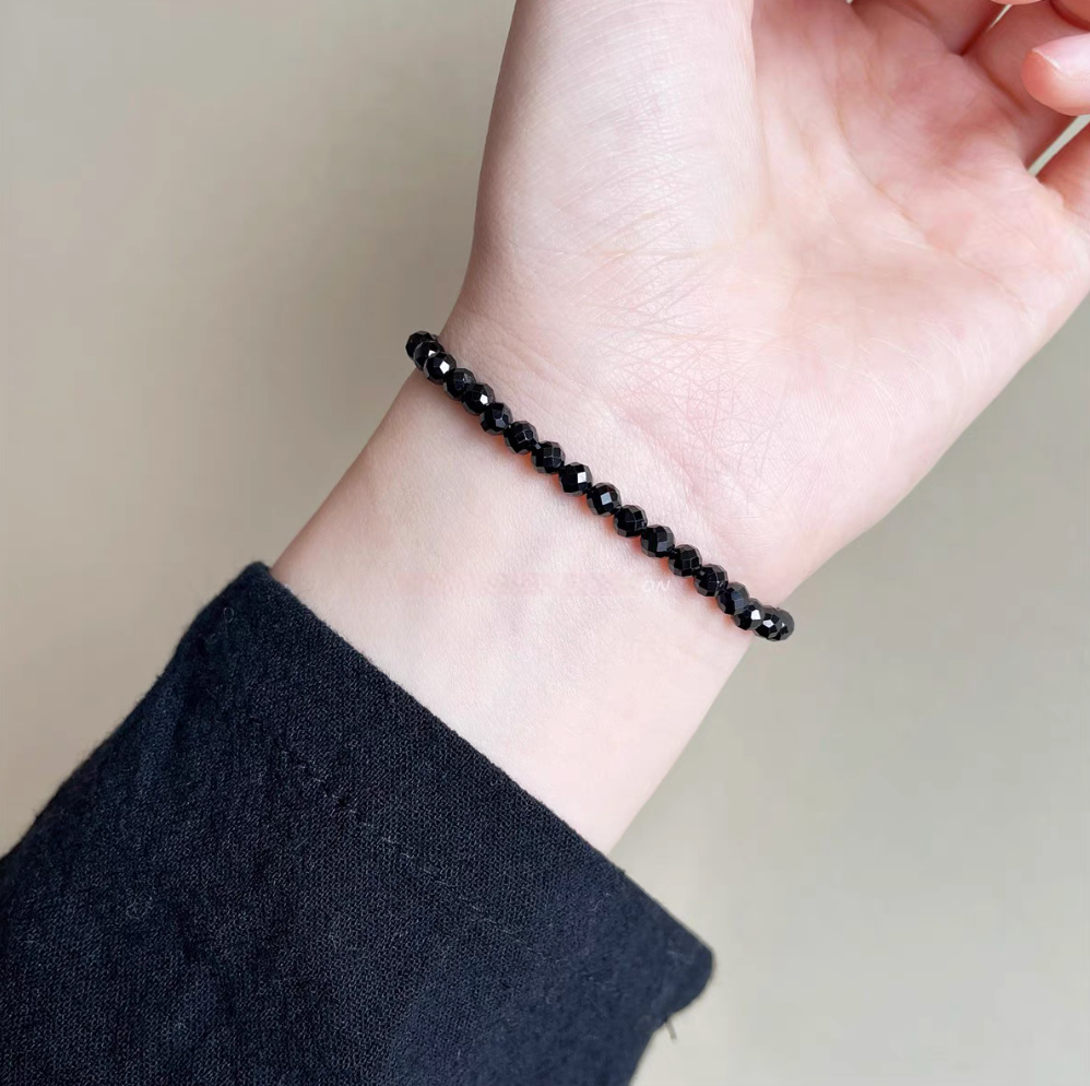 Minimalist black spinel beaded bracelet worn on wrist with faceted crystal beads for a sleek elegant look