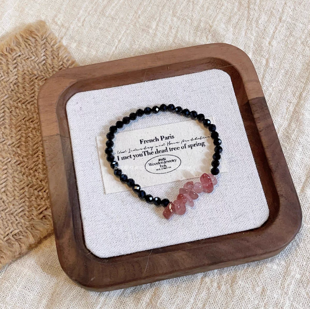 Strawberry quartz and black spinel beaded bracelet with polished pink crystal chips on neutral display background