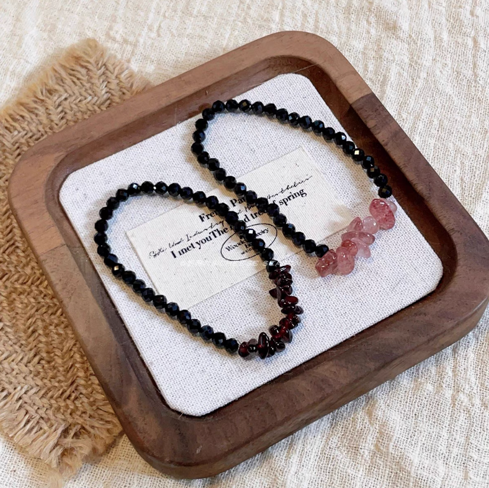 Black spinel bracelet set with strawberry quartz and garnet stone accents arranged together on fabric display tray