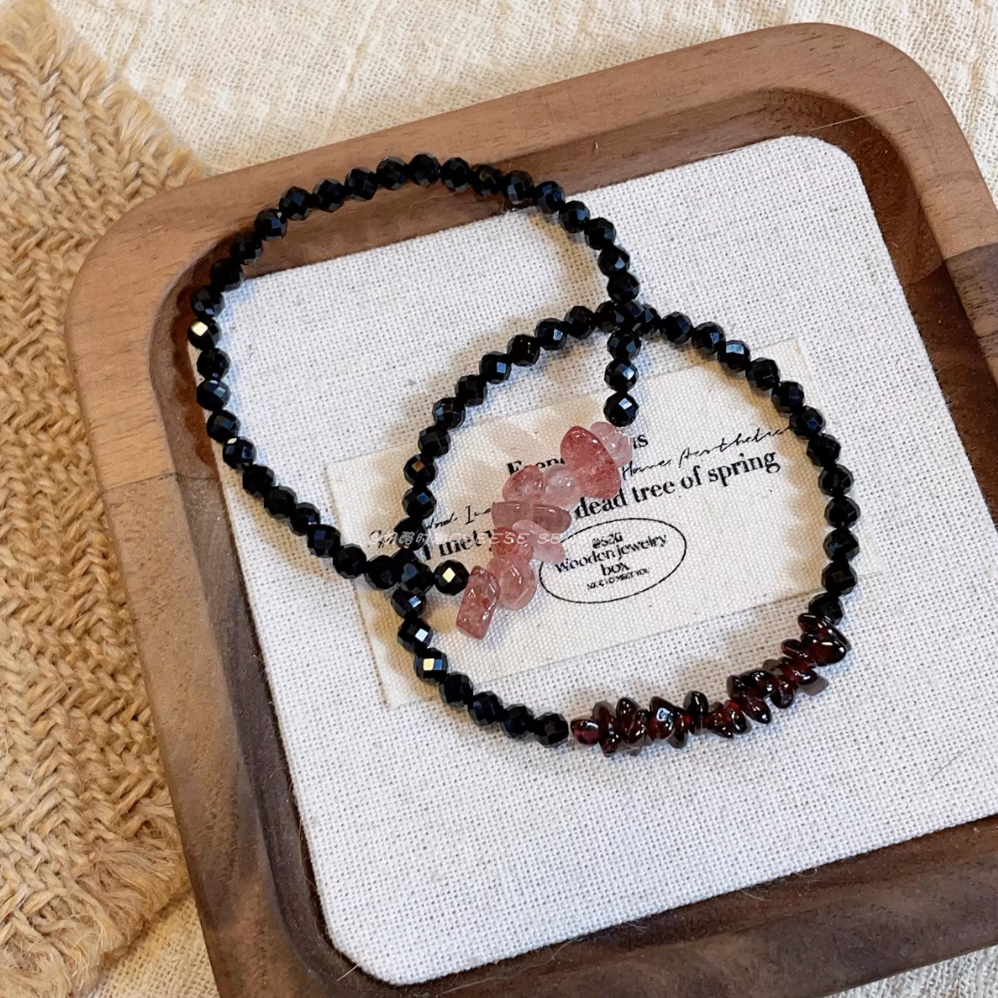 Elegant crystal and garnet bracelet set featuring black spinel beads with strawberry quartz and garnet accents displayed on linen tray
