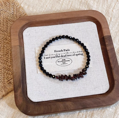 Black spinel bracelet with deep red garnet chip beads displayed on linen tray for elegant minimalist style