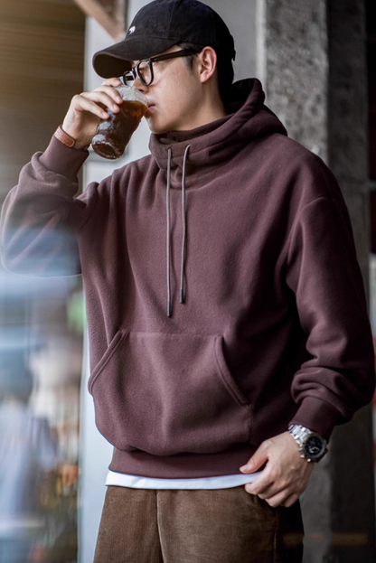 Man wearing Elevate Shield Hoodie in chestnut red with visor hood while drinking coffee showcasing comfort and everyday versatility