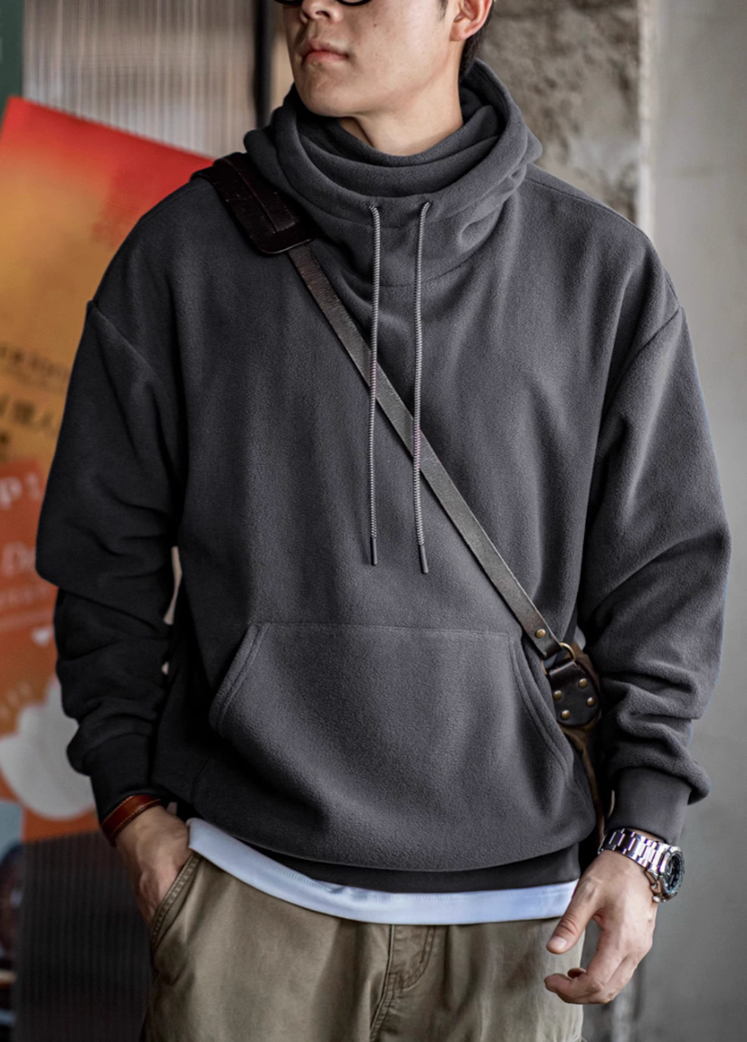 Elevate Shield Hoodie in dark gray featuring semi-high collar and relaxed fit styled with crossbody bag for urban layering