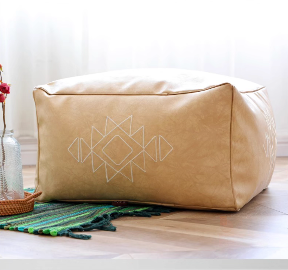 Khaki embroidered square bean bag sofa with white geometric pattern placed on a wooden floor with decorative elements