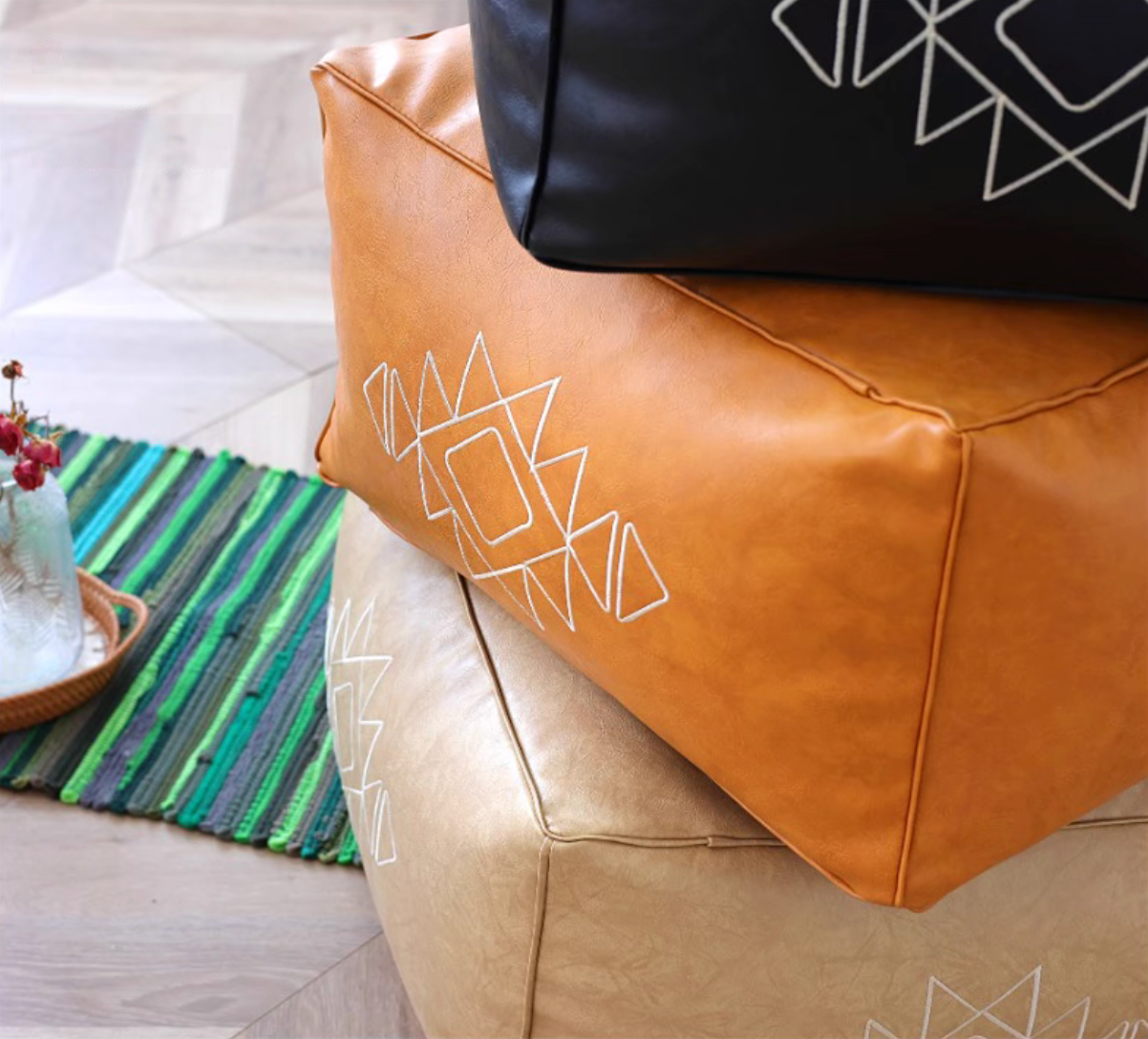 Close-up of stacked orange yellow and khaki embroidered square bean bag sofas with geometric embroidery details