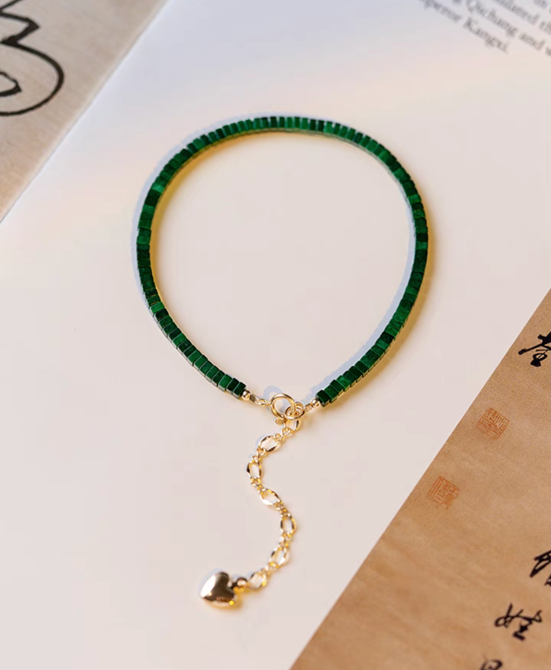 Full view of seaweed green malachite bracelet with gold clasp and extension chain displayed flat