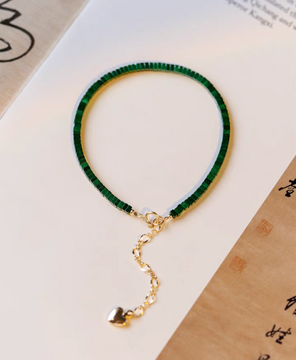 Full view of seaweed green malachite bracelet with gold clasp and extension chain displayed flat