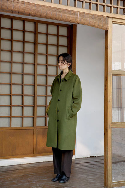 Army green long wool coat standing front view with hands in pockets and sleek straight cut fit
