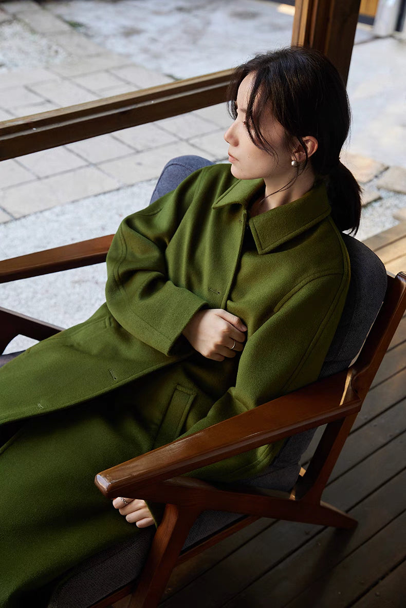 Army green wool overcoat seated styling view highlighting soft texture and relaxed sleeve fit
