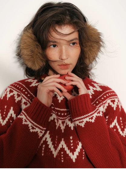 Close-up of red and cream Fair Isle merino wool sweater showing the circular yoke pattern as the model holds a pear near her face.