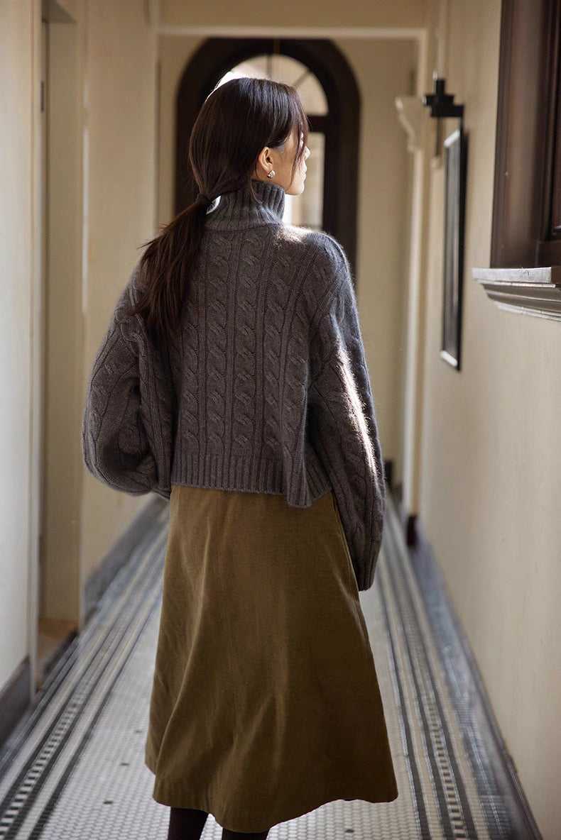 Back view of dark gray cable-knit turtleneck sweater showing relaxed fit and detailed knit pattern