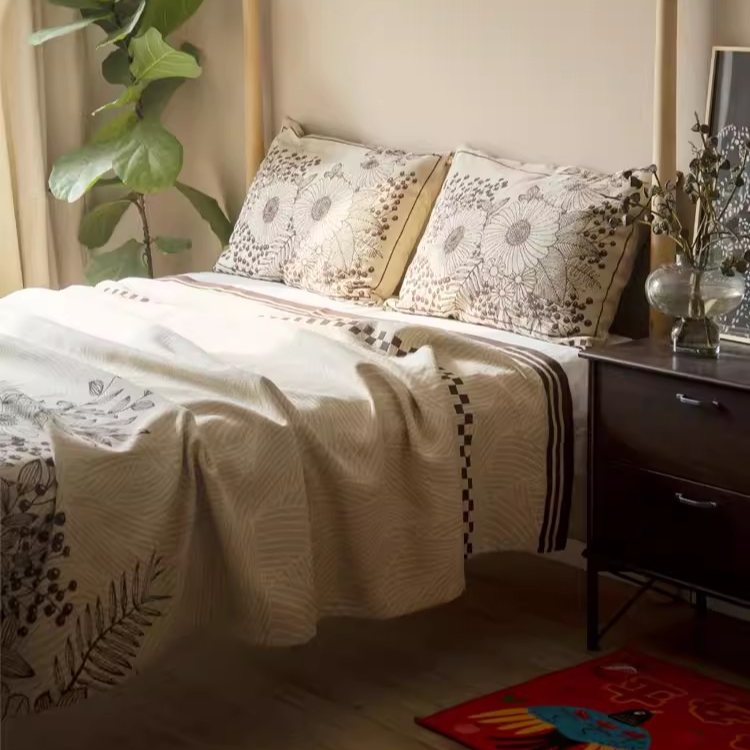 Floral Cotton Gauze Blanket Elegant Splendor styled on a cozy bedroom bed with botanical printed pillows
