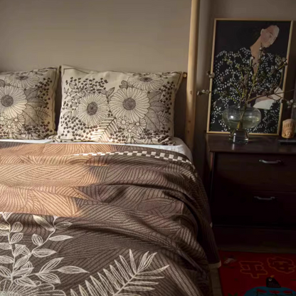 Floral Cotton Gauze Blanket Elegant Splendor brown leaf pattern displayed across a bedroom bed with botanical pillows