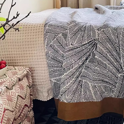 Floral Cotton Gauze Blanket Leaf Vein displayed on a bed beside a textured cotton blanket with modern bedroom decor