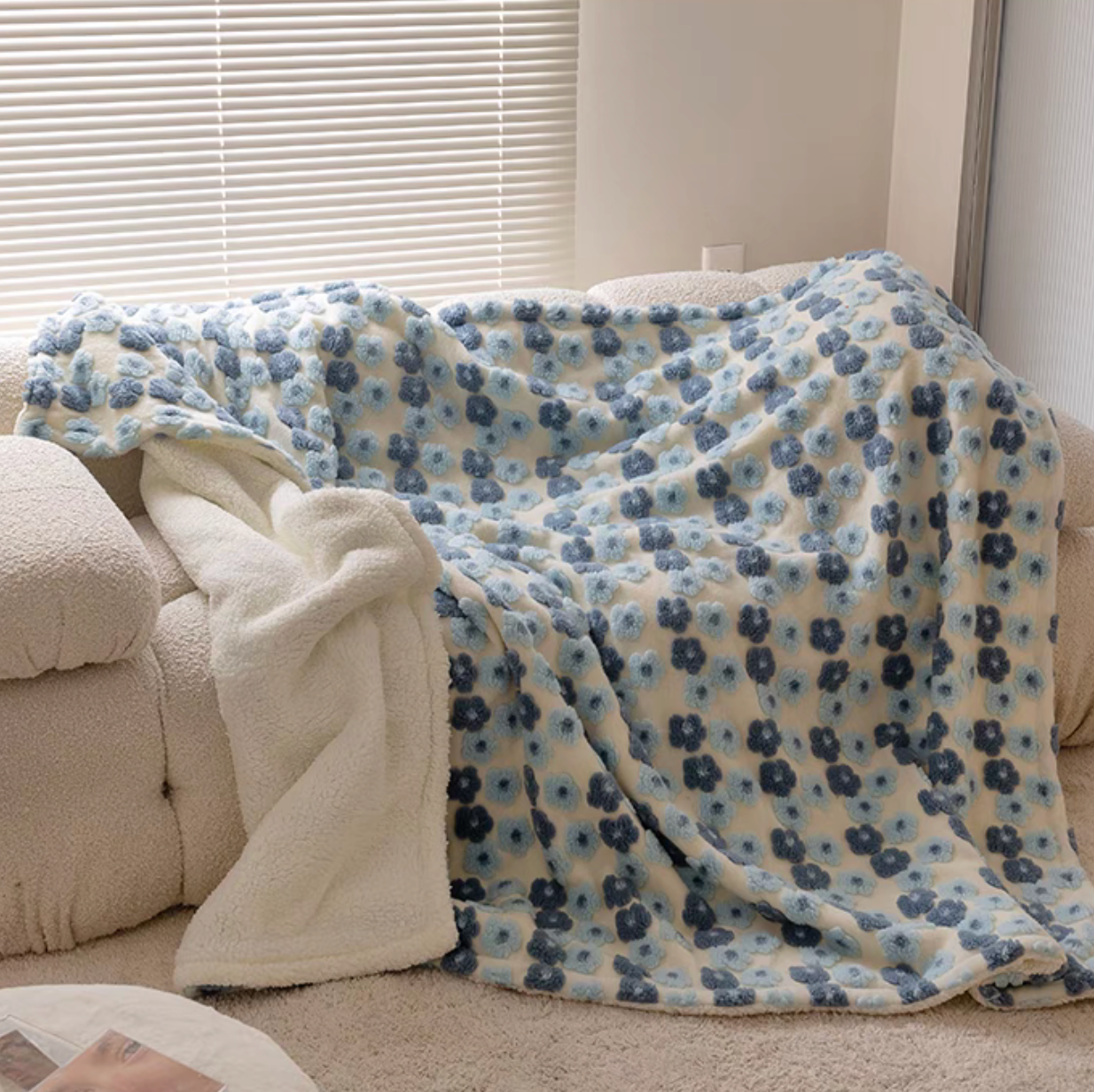 Jacquard Blue floral fleece throw blanket draped over sofa with soft lighting