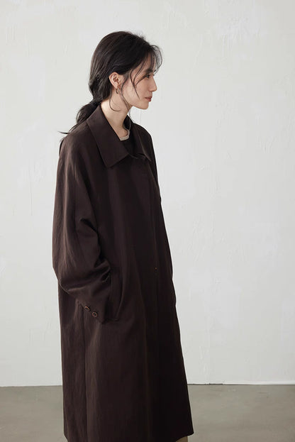 Side profile of the coffee brown fluid-drape Tencel trench coat, showing straight long line and pockets.